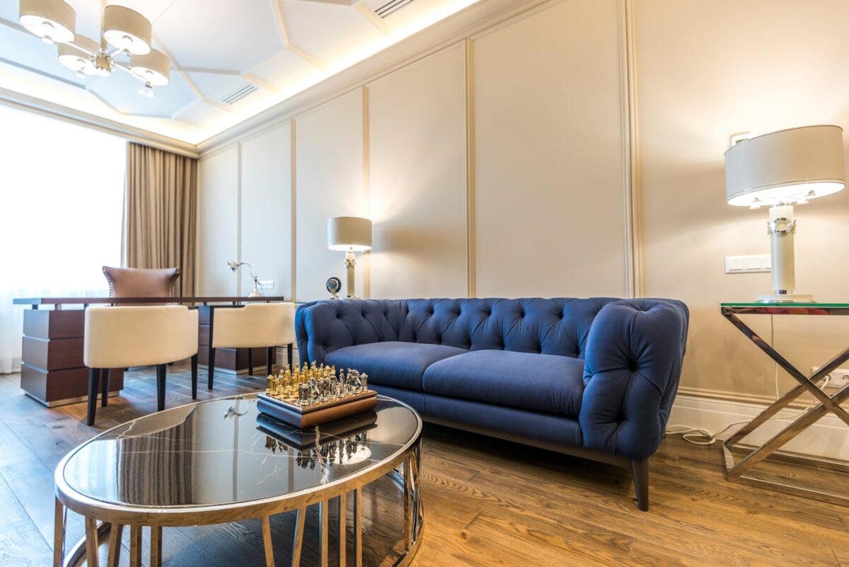 Bright modern living room featuring a blue couch, elegant decor, and ample natural light.