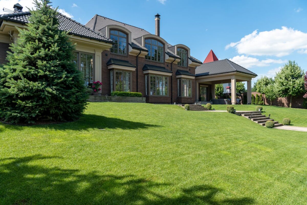 Luxury estate with manicured lawn and modern architectural design on a sunny day.